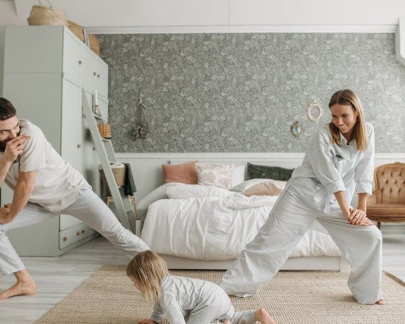 A joyful family bonding through morning stretches in a cozy bedroom setting.